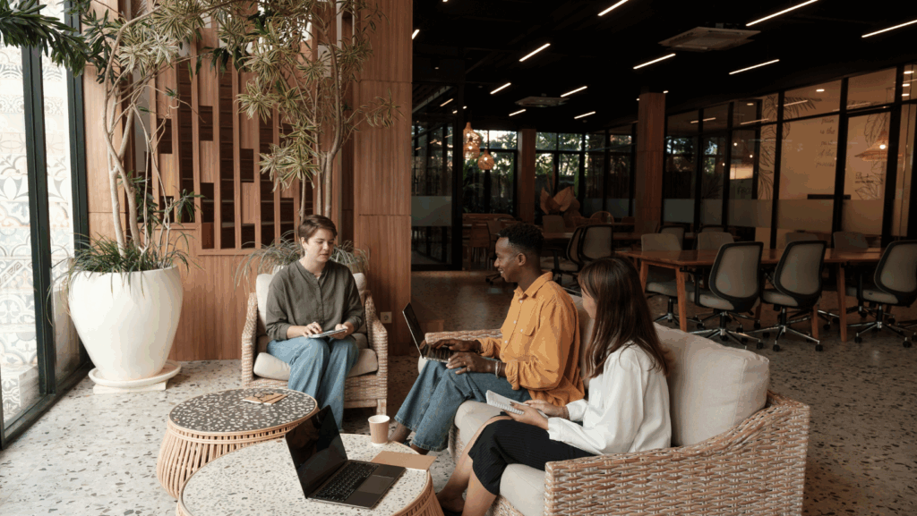 trois personnes qui parlent dans des fauteuils dans un espace de travail. 
