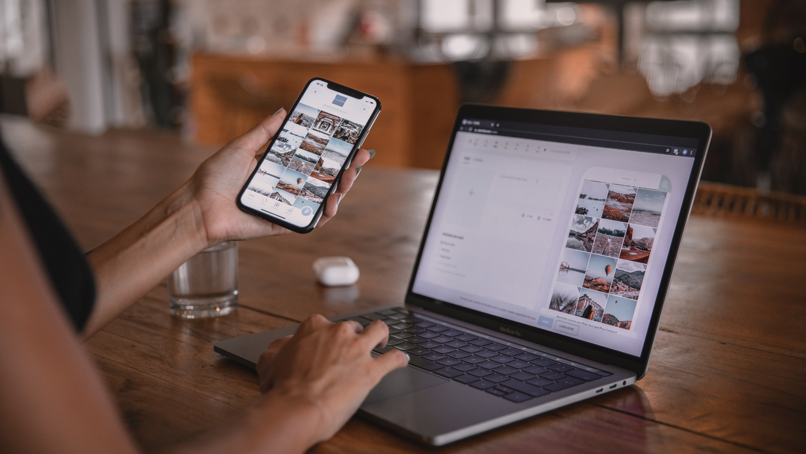 Femme qui tient son téléphone dans la main gauche et qui est aussi devant son ordinateur et semble travailler.